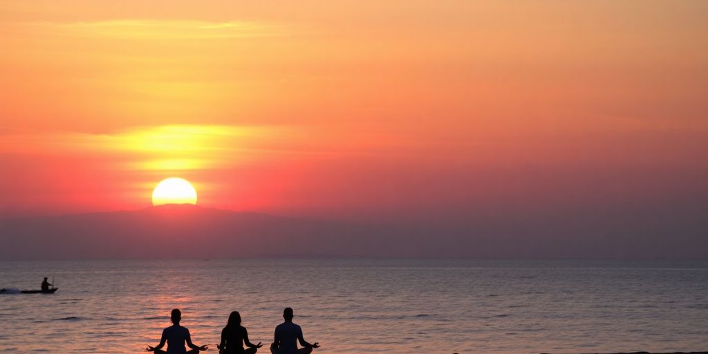 People meditating on a beach at sunset.