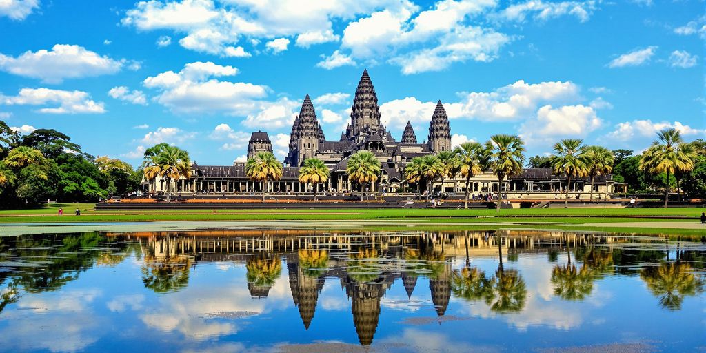 Angkor Wat towers reflected in calm water with greenery.