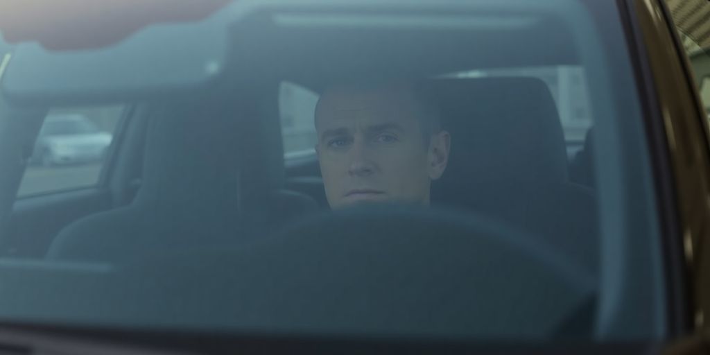 Andrew Tate in a luxurious car, dark setting.