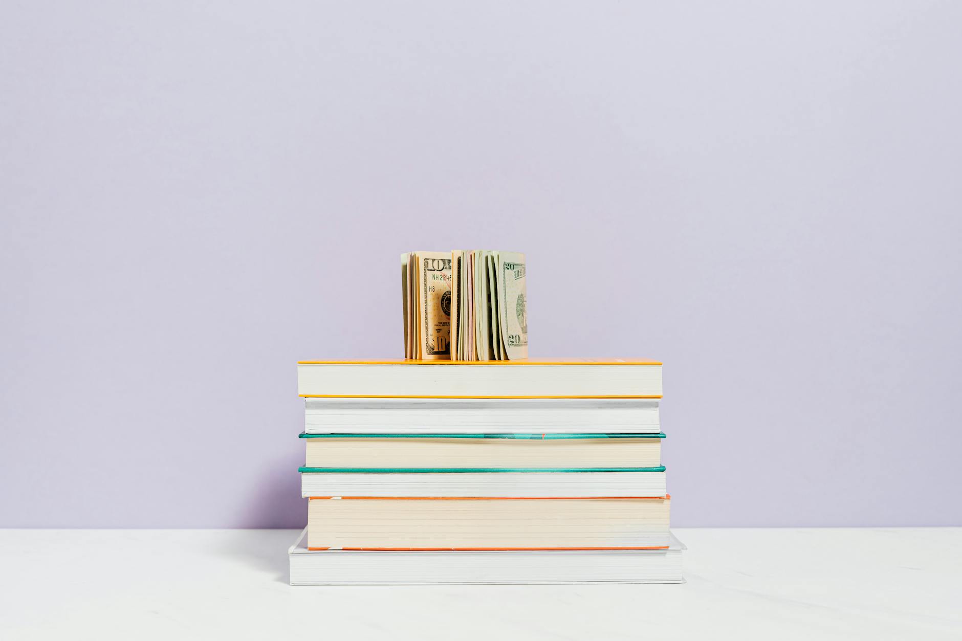 Stack of business books with US dollar bills - Alex Hormozi $100M Offers