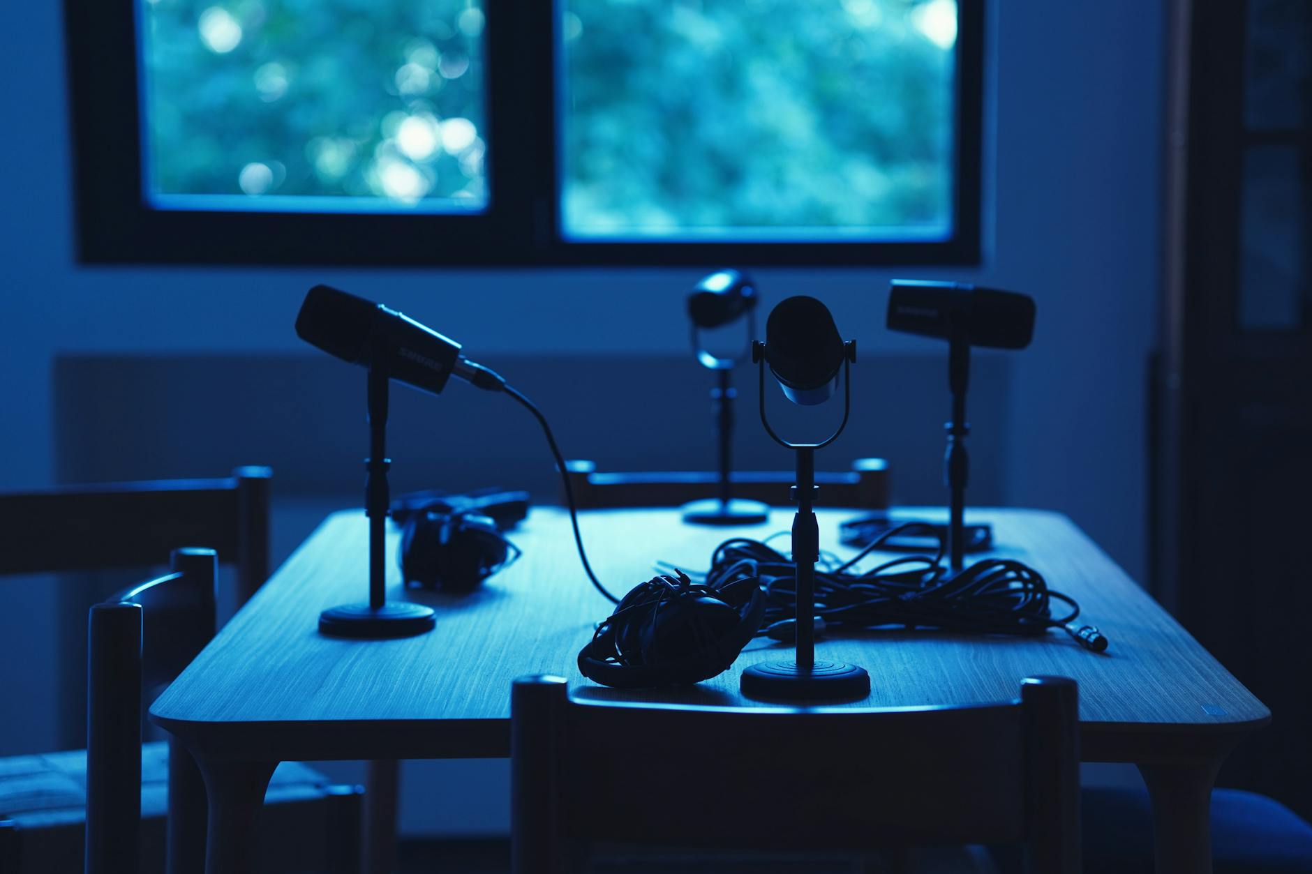 Dimly lit podcast studio with microphones and headphones on a table