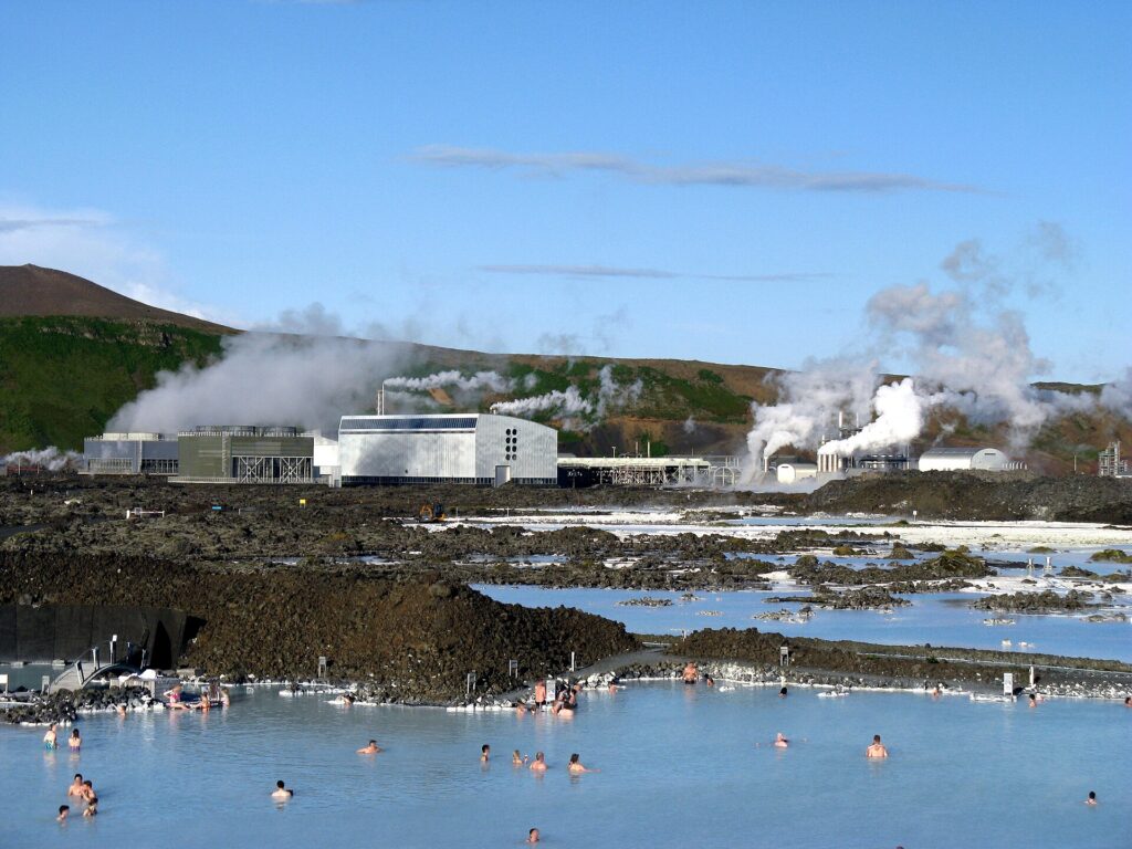 Badgasten in de Blue Lagoon met de dampende geothermische centrale Svartsengi op de achtergrond