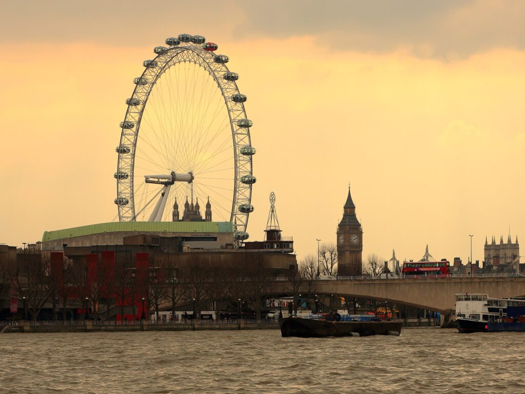 De London Eye en de Big Ben bij zonsondergang boven de Theems