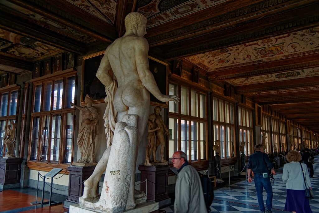 Klassieke Romeinse beelden langs een gang met fresco's in de Uffizi