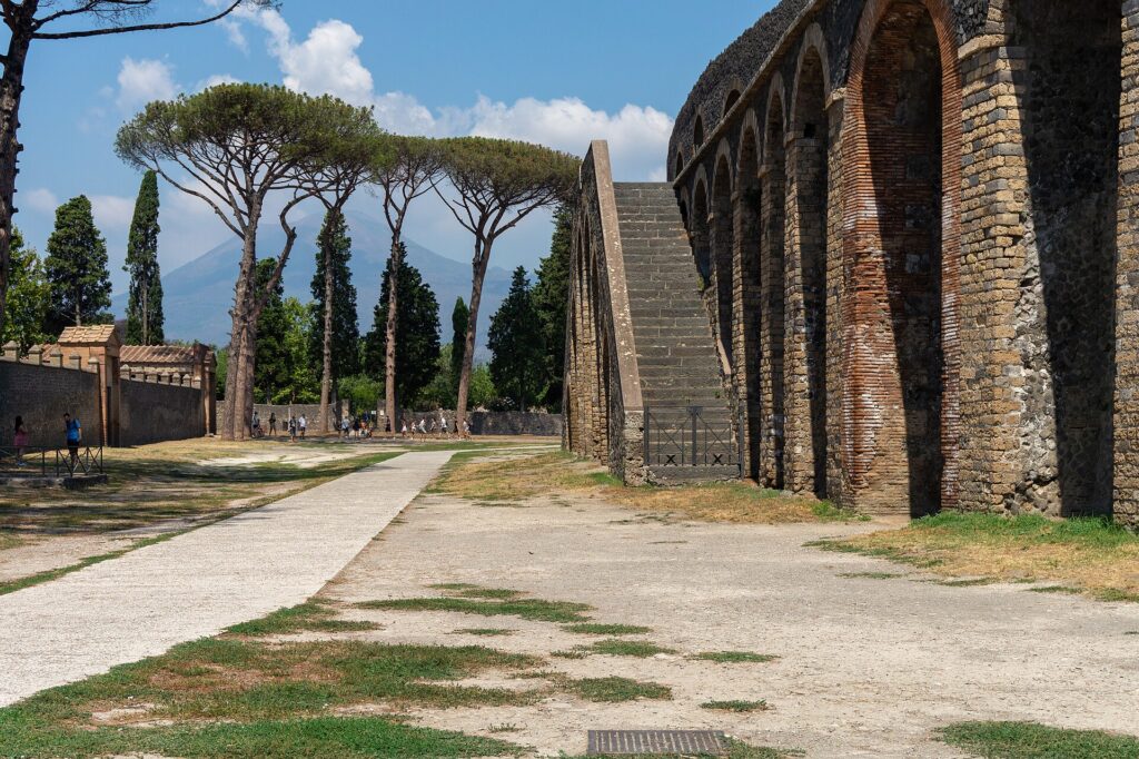 Buitenkant van het Amfitheater van Pompeï met parasoldennen en de Vesuvius