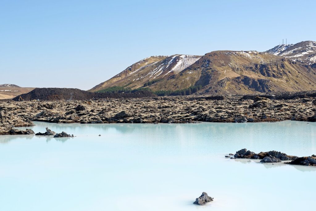 Milky blue water of the Blue Lagoon in Iceland surrounded by moss-covered lava and Mount Þorbjörn