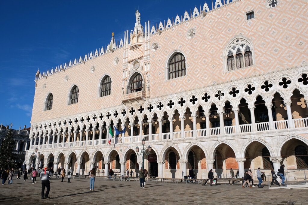 The Gothic arcaded façade of the Doge's Palace in Venice under a blue sky