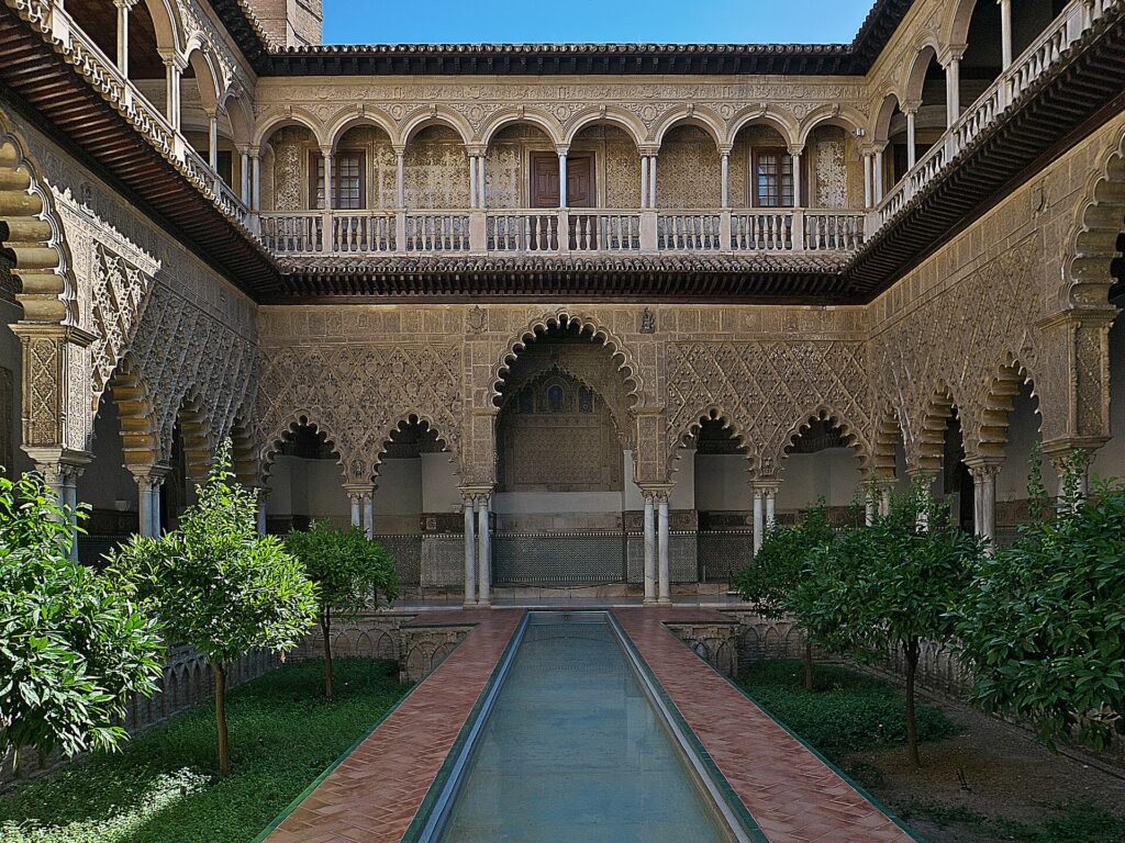Patio de las Doncellas in the Real Alcázar of Seville with its long pool, orange trees and carved arches
