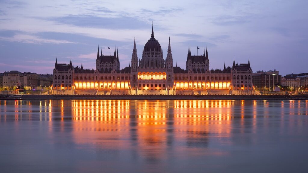 Das beleuchtete Parlament in Budapest in der Abenddämmerung, gespiegelt in der Donau