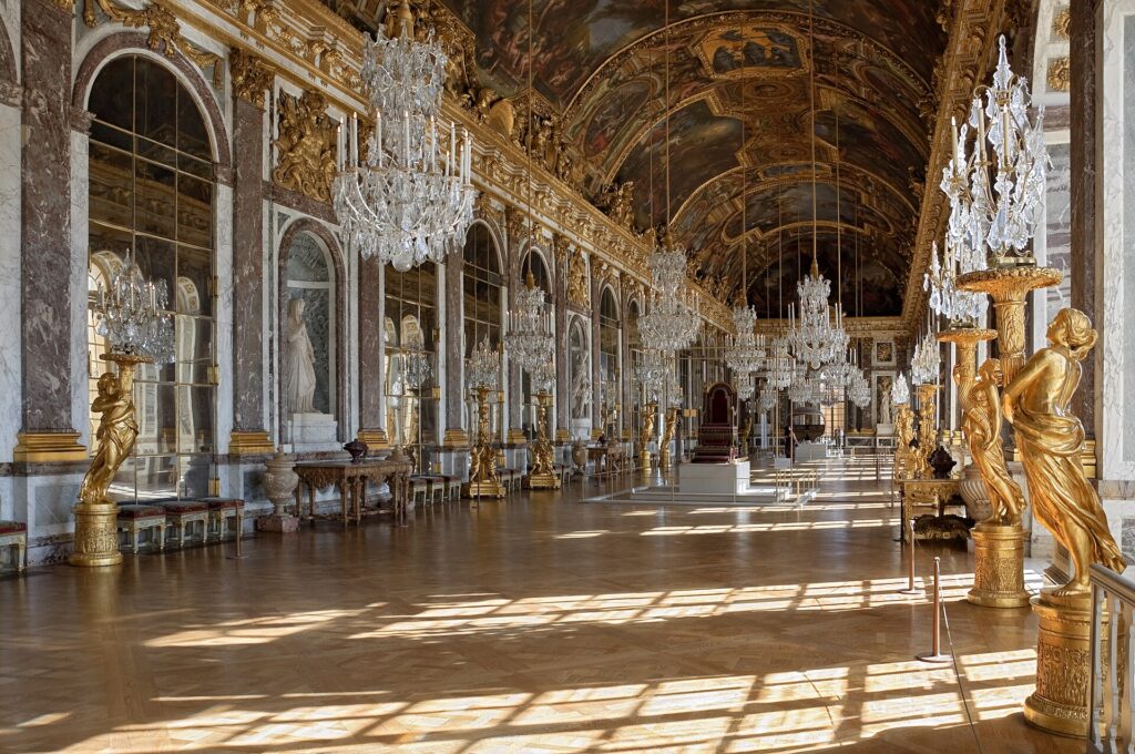Der Spiegelsaal in Schloss Versailles mit Kristalllüstern und vergoldeten Statuen