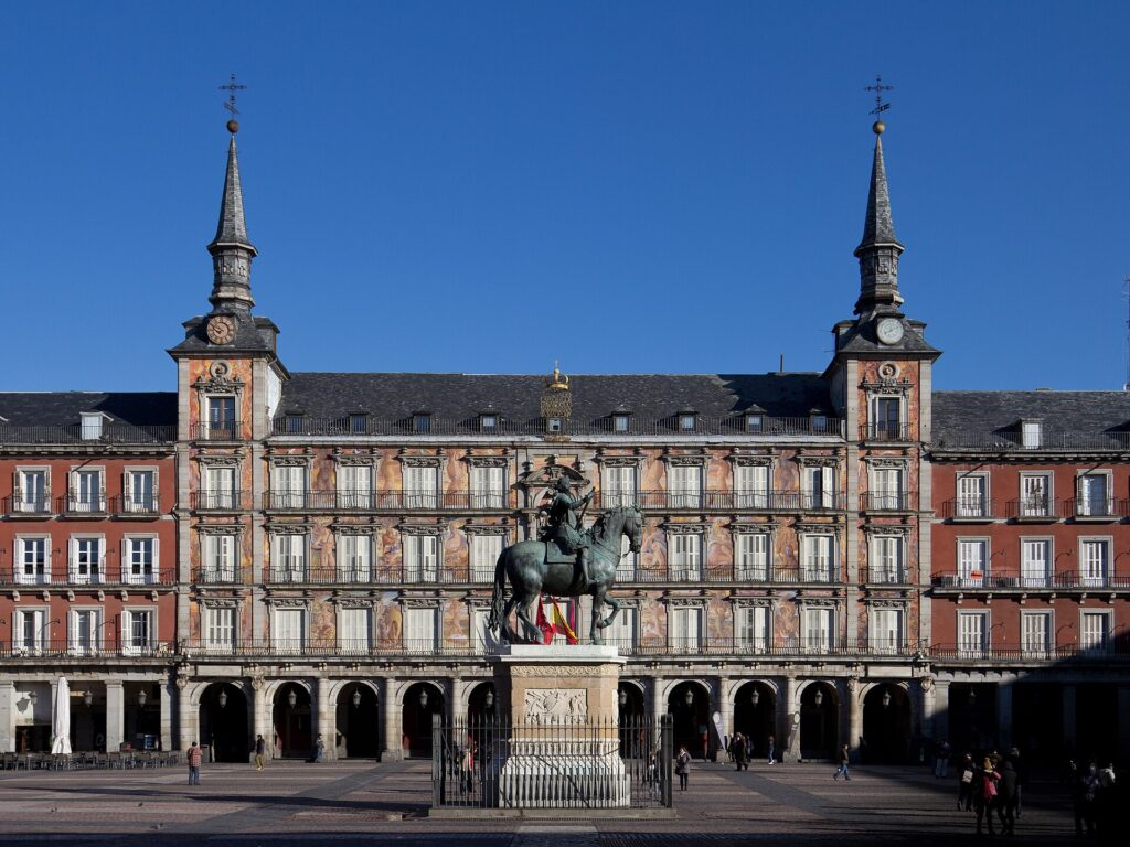 Die Plaza Mayor in Madrid mit roten Arkadenfassaden und dem Reiterstandbild Philipps III.