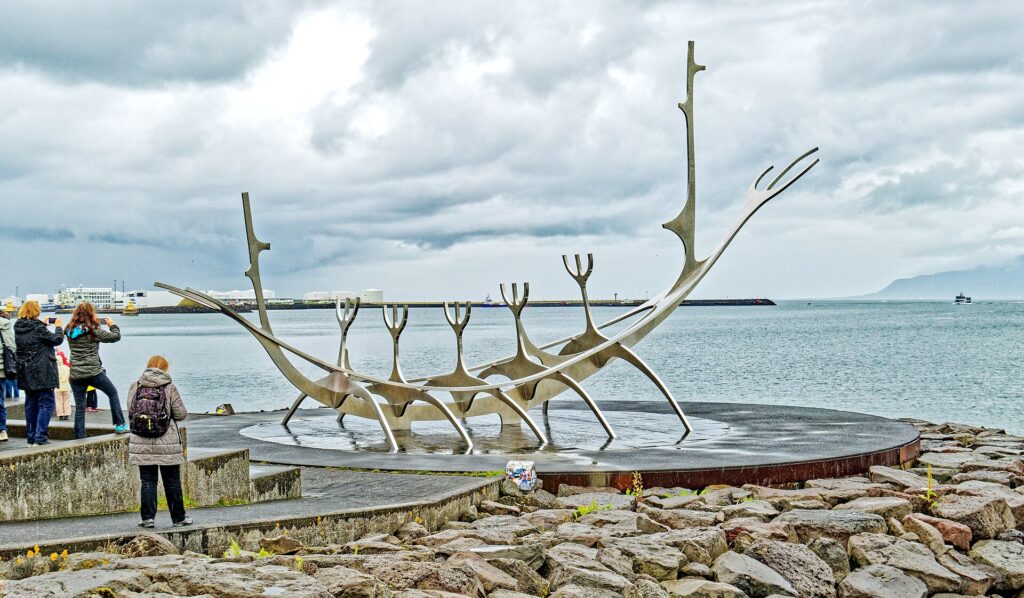 Die Stahlskulptur Sonnenreisender (Sólfar) an der Uferpromenade von Reykjavík mit dem Berg Esja jenseits der Bucht