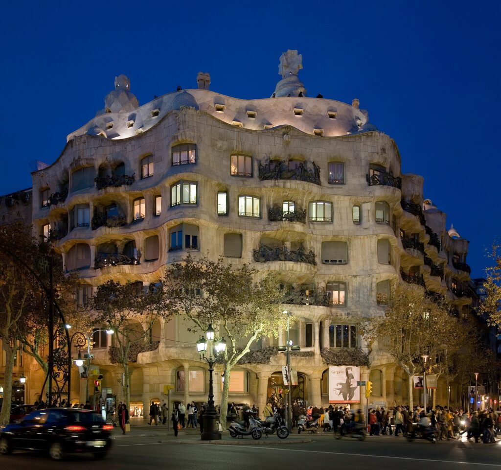 The wavy stone façade of Casa Milà (La Pedrera) on Passeig de Gràcia, lit up at dusk