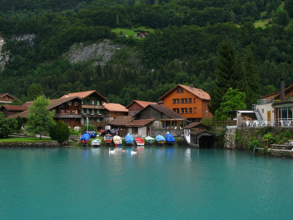 Wooden houses and boats on the turquoise water of Lake Brienz at Iseltwald