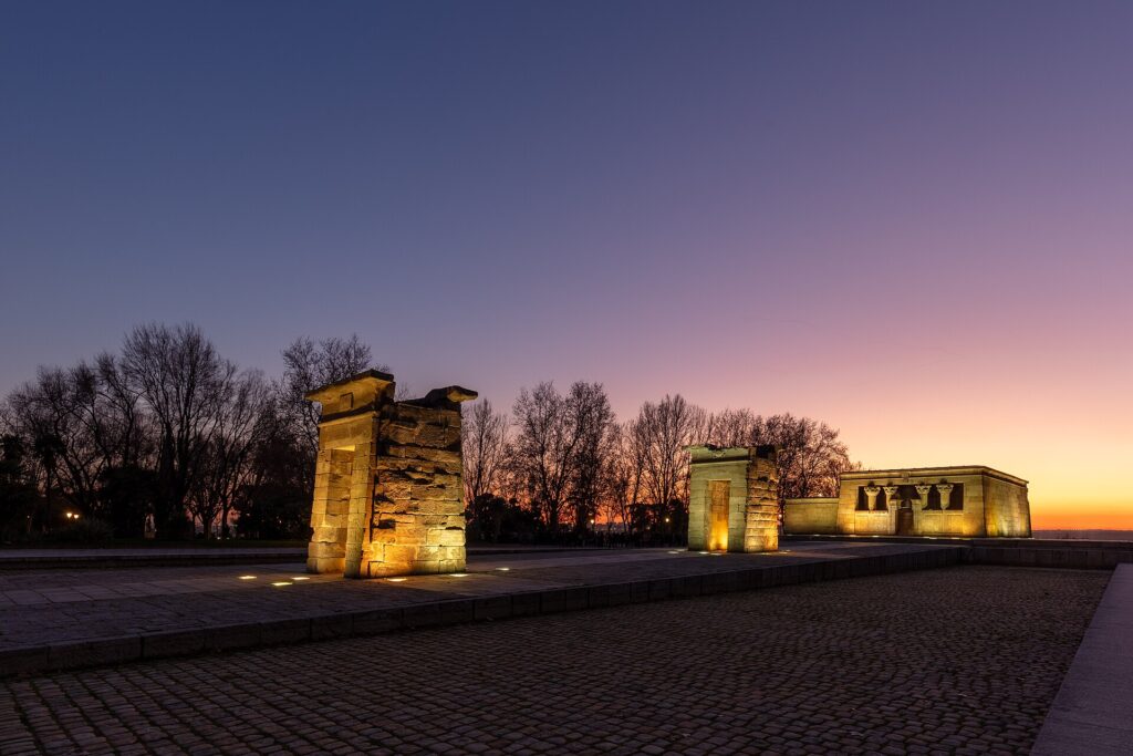 The ancient Egyptian Temple of Debod in Madrid silhouetted against a purple and orange sunset sky