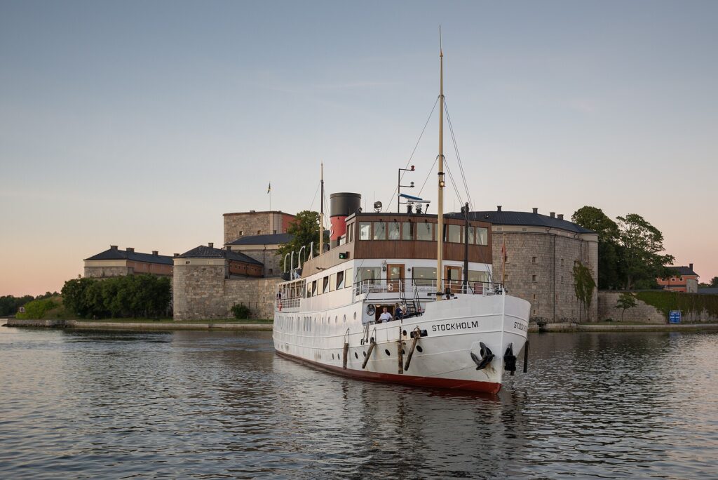 The white steamboat S/S Stockholm arriving at Vaxholm with Vaxholm fortress behind
