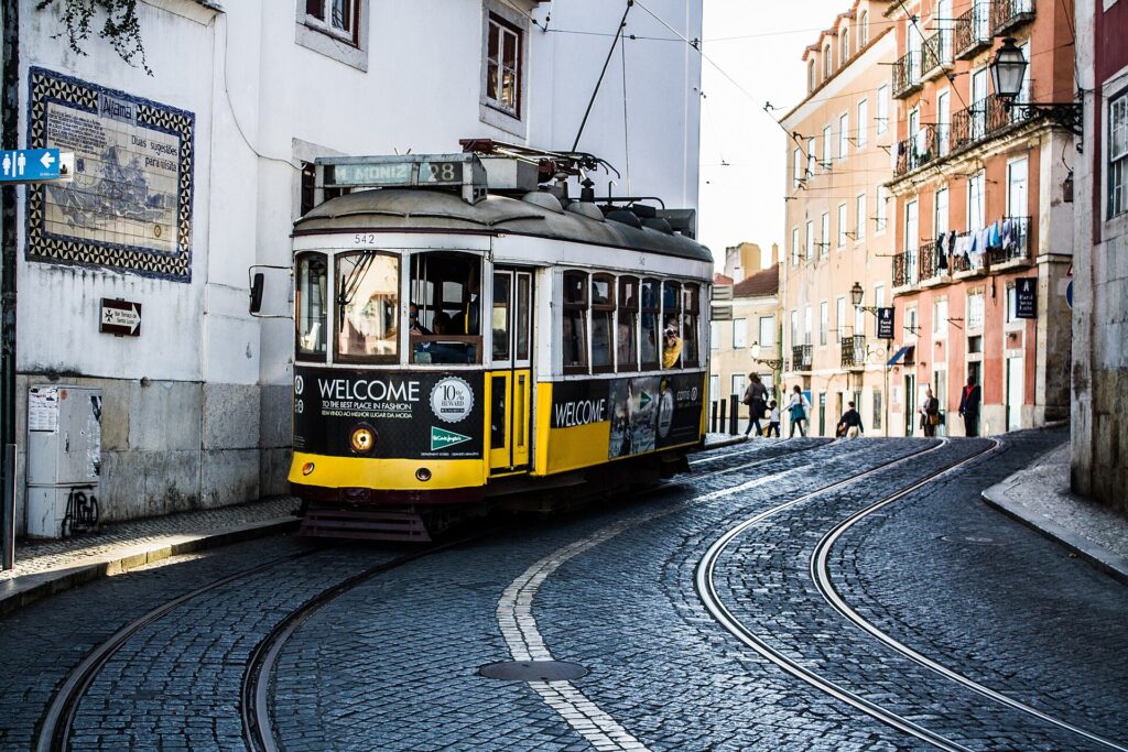 Gele tram 28 in een bochtige straat met kinderkopjes in Alfama, Lissabon