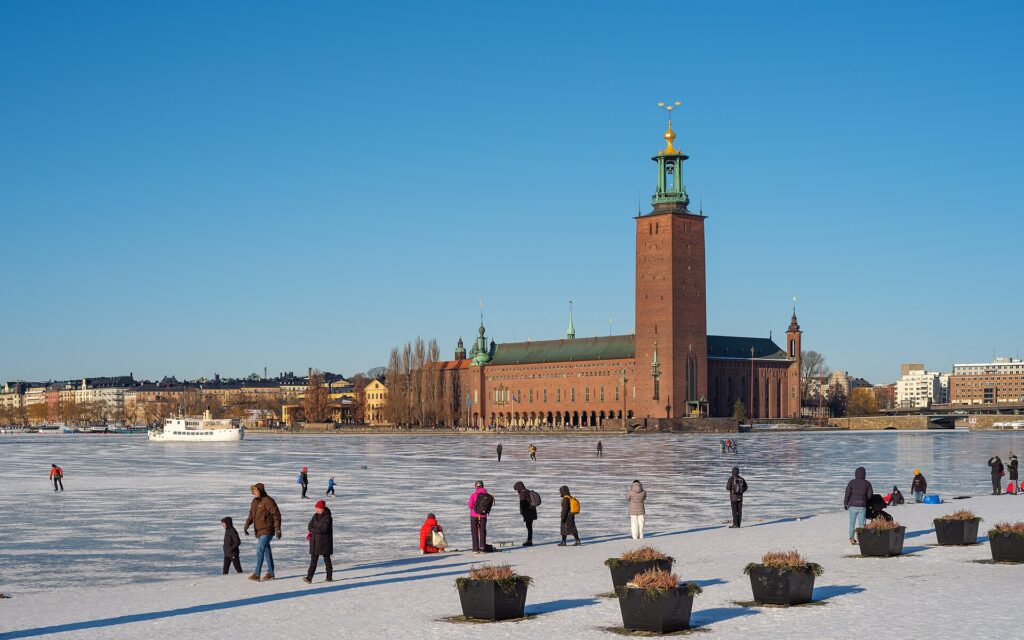 Het stadhuis van Stockholm met toren en drie gouden kronen, gezien over bevroren water vanaf Riddarholmen