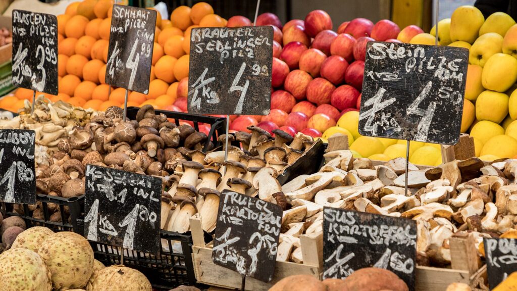 Marktstand am Wiener Naschmarkt mit Pilzen, Äpfeln und Orangen