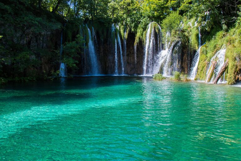 Watervallen die in een turquoise meer stromen in Nationaal Park Plitvicemeren, Kroatië
