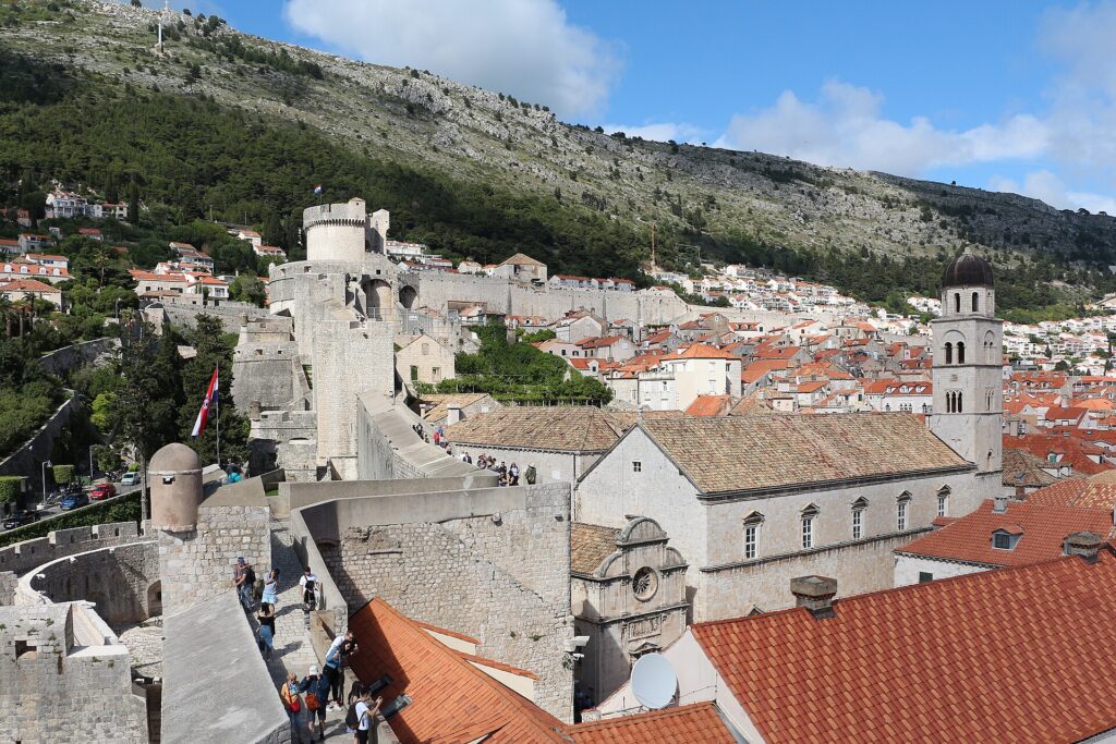 Bezoekers lopen over de stadsmuren van Dubrovnik boven de daken van de oude stad